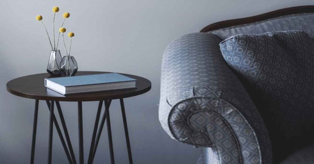 A side table next to a blue couch, featuring a book placed on top