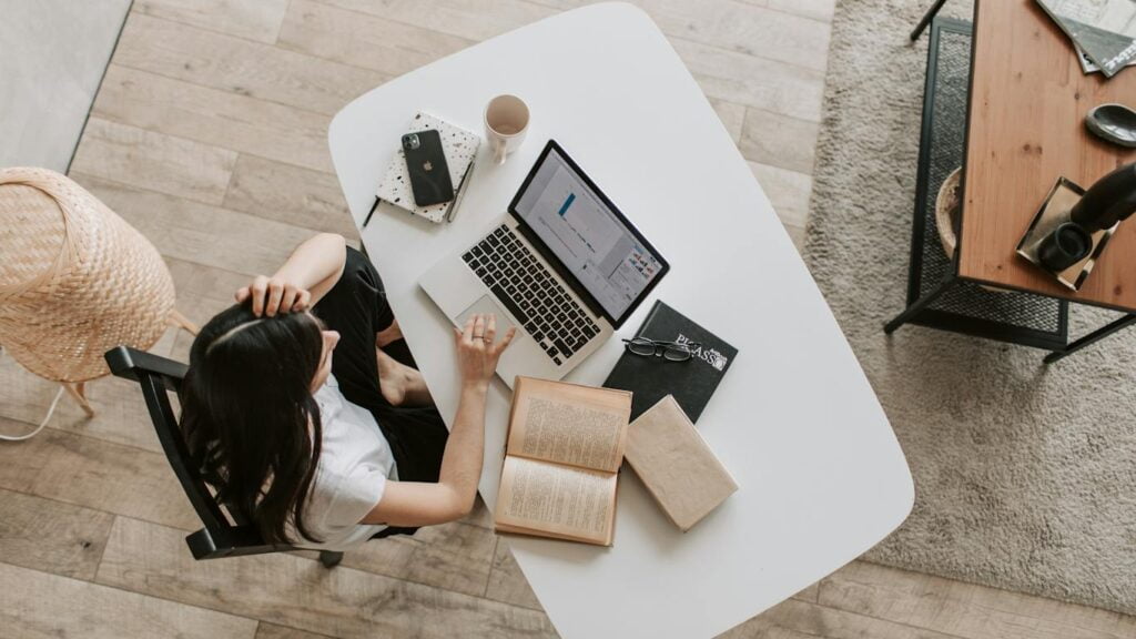 A young woman engrossed in her laptop, sitting at a study table, deep in concentration